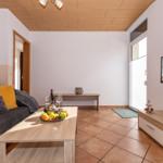 Wohnzimmer mit Sofa, Couchtisch und Fernseher an der Wand.