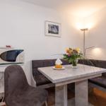 Essbereich mit Tisch, Sitzbank und Stuhl. Mikrowelle und Blumen auf Tisch.