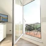 Wohnzimmer mit TV und Balkon mit zwei Stühlen.