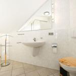 Badezimmer mit Waschbecken, Spiegel, Toilette und Dusche.