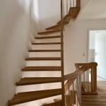 Holztreppe mit Metallgeländer führt zur oberen Etage.