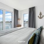Schlafzimmer mit Blick auf Hafen und Wasser, Wanddekoration mit Ankermotiv.