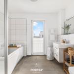 Badezimmer mit Badewanne, Dusche und Fenster zum Balkon.