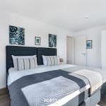 Schlafzimmer mit Doppelbett, Wandbildern und Kleiderschrank.