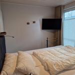 Schlafzimmer mit Bett, Fernseher und Fenster.