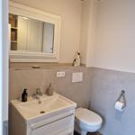 Badezimmer mit Waschbecken, Spiegel und Toilette