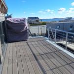 Terrasse mit Holzdecke und Blick auf Wasser und moderne Häuser.