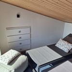 Schlafzimmer mit Bett, Kleiderschrank und Sitzkissen unter Holzdecke.