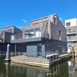 Modernes Wasserhaus mit Balkon und Bootsanlegestelle am Kanal.