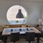 Esszimmer mit runden Fenster, Holztisch und schwarzen Stühlen.