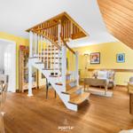 Wohnbereich mit Holztreppe, gelben Wänden und Wohnmöbeln.