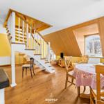 Haus mit Holzverkleidung, Treppe und Essbereich mit Tisch und Stühlen.