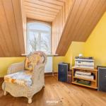 Dachgeschosszimmer mit Wickerstuhl, Vinyl-Spieler und Holzdecke.