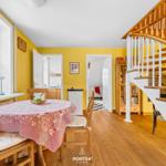 Esszimmer mit Holztisch, gelben Wänden und Holzboden. Treppe führt zur oberen Etage.