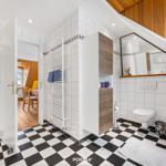 Badezimmer mit Dusche, Toilette und Spiegelschrank unter Dachschrägen.