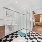 Badezimmer mit Dusche, Waschbecken und schwarz-weißem Boden