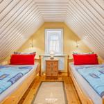 Zwei Betten mit blauen Bettwäschen unter schrägen Holzwänden.