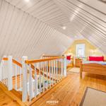 Dachgeschosszimmer mit Holzboden, zwei Betten und Holzgeländer.
