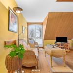 Wohnzimmer mit Rattanmöbeln, Fernseher und Balkontür.