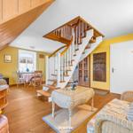 Wohnbereich mit Holzdecke, Treppe und Essbereich. Möbel aus Rattan und Holz.