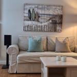 Wohnzimmer mit Sofa, Couchtisch und Wandbild mit Surfbrettern.