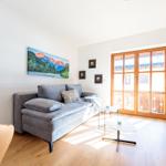 Wohnzimmer mit Sofa, Tischen und Fenster zur Terrasse.