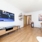Wohnbereich mit Fernseher, Esstisch und Wandbild
