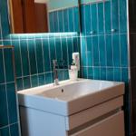 Badezimmer mit blauen Fliesen, Waschbecken und Spiegel.
