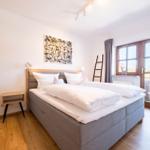 Schlafzimmer mit Doppelbett, Holzboden und Fenster mit Blick.