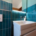 Badezimmer mit blauen Fliesen, Waschbecken und Spiegel.