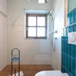 Badezimmer mit Dusche, Fenster und blauen Fliesen.