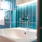 Waschbecken mit modernem Wasserhahn und blauen Fliesenwand.