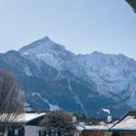 Schneekappen bedecken die Berge. Schnee liegt auf Dächern und Bäumen.