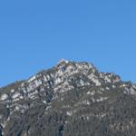 Hoher Berg mit Felsformationen und Wald unter blauem Himmel