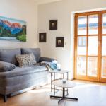 Wohnzimmer mit Sofa, Tischen und Blick auf Balkon