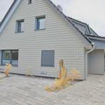 Moderne Ferienwohnung mit grauer Fassade und gepflastertem Vorplatz.
