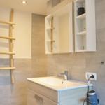 Bad mit Waschbecken, Spiegelschrank und Holzhandtuchhalter.