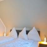 Schlafzimmer mit Doppelbett, weißen Kissen und Nachttischlampen.