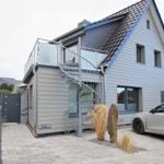 Moderne Villa mit Dachterrasse und spiralförmiger Außentreppe. Parkplatz mit gepflastertem Hof.