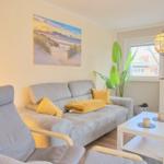 Wohnzimmer mit grauem Sofa, gelben Kissen und Wandbild