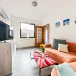 Wohnzimmer mit orangefarbenem Sofa, TV und Fenster.