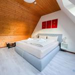 Schlafzimmer mit Holzwand, Bett und Fenster