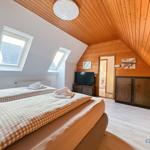 Schlafzimmer mit Dachschrägen, zwei Fenstern und Bett mit Tisch.