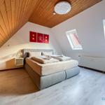 Schlafzimmer mit Dachschrägen, Bett, Fenster und Holzdecke.