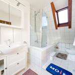 Badezimmer mit Dusche, Toilette und Waschbecken. Holzfenster und maritime Dekoration.