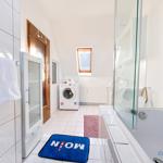 Badezimmer mit Badewanne, Dusche, Waschmaschine und Fenster.