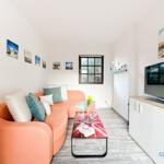 Wohnzimmer mit orangefarbenem Sofa, Glas-Tisch und Fernseher.