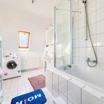 Badezimmer mit Dusche, Waschmaschine und Fenster.