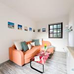 Wohnzimmer mit orangefarbenem Sofa, Couchtisch und Fenster.