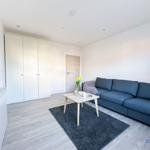 Wohnzimmer mit blauem Sofa, Tisch und Teppich. Hintergrund: weiße Wände und Kleiderschrank.